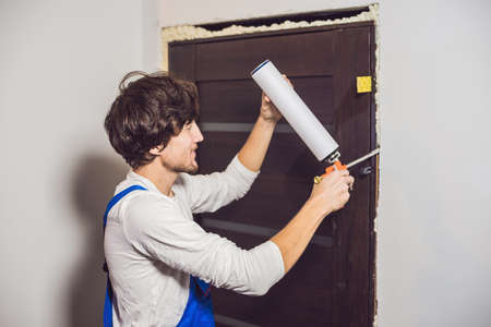 Young handyman installing door with an mounting foam in a room.の写真素材