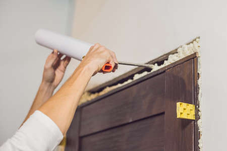 Young handyman installing door with an mounting foam in a room.の写真素材