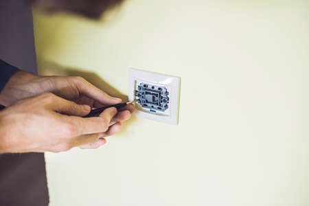 A young electrician installing an electrical switch in a new house.