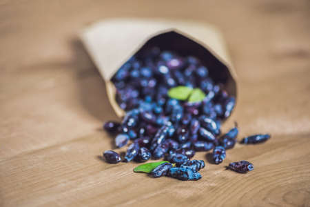 Fresh honeysuckle blue berry fruits with leaf on a wooden background.の写真素材