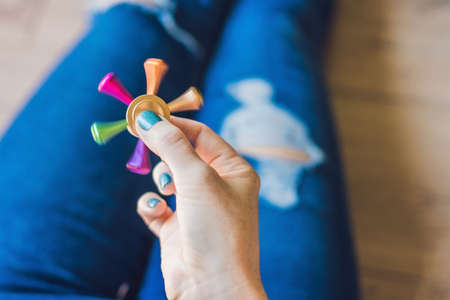Girl teenager in holey jeans holds in hands and plays with spinner.の写真素材