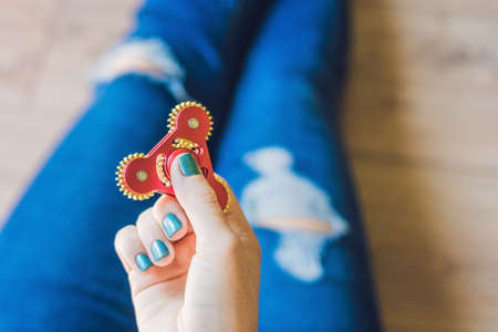 Girl teenager in holey jeans holds in hands and plays with spinner.の写真素材