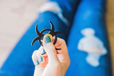 Girl teenager in holey jeans holds in hands and plays with spinner.の写真素材