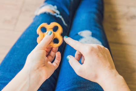 Girl teenager in holey jeans holds in hands and plays with spinner.の写真素材