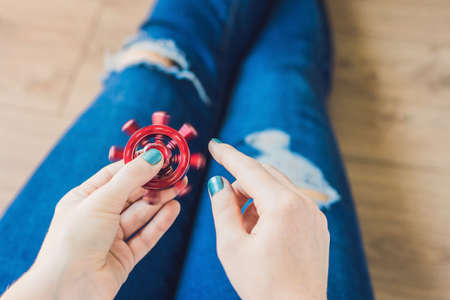 Girl teenager in holey jeans holds in hands and plays with spinner.の写真素材
