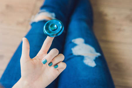 Girl teenager in holey jeans holds in hands and plays with spinner.の写真素材