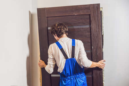 Young handyman installing door with an mounting foam in a room.の写真素材