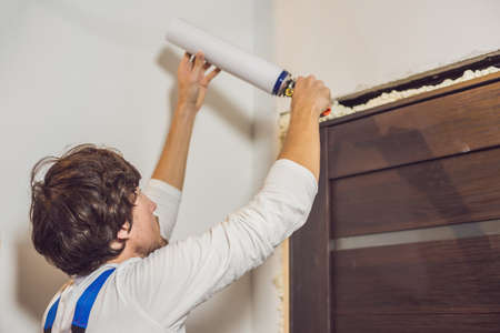 Young handyman installing door with an mounting foam in a room.の写真素材