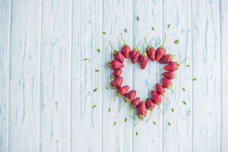 Fresh strawberries array heart shape on old wooden background.の写真素材