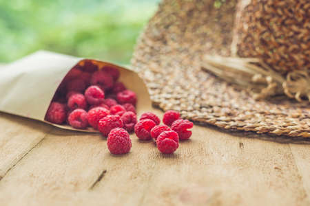 Summer holiday, vacation, relaxation concept. Raspberries, straw hat, on wooden background. Free text copy space. Summer vibes conceptの写真素材