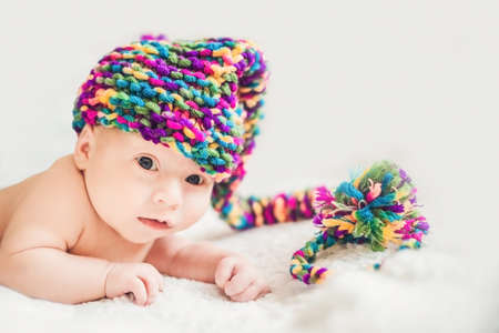 newborn baby in New Year's gnome Cap lays On a white blanket.の写真素材
