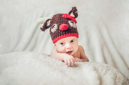 Happy smiling infant baby boy portrait dressed in christmas deer crocheted hat, winter holidays concept.の写真素材