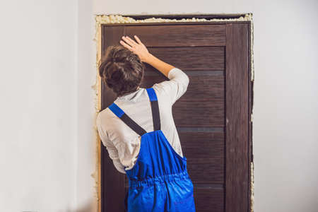 Young handyman installing door with an mounting foam in a room.の写真素材