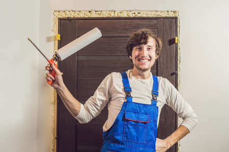 Young handyman installing door with an mounting foam in a room.の写真素材