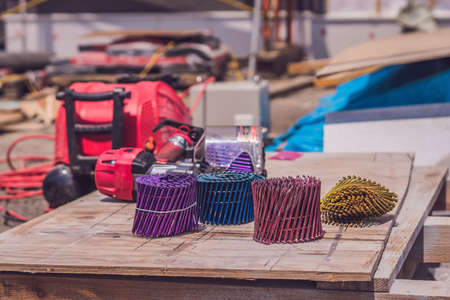 Multicolored nails for pneumatic nail gun on a wooden background.の写真素材