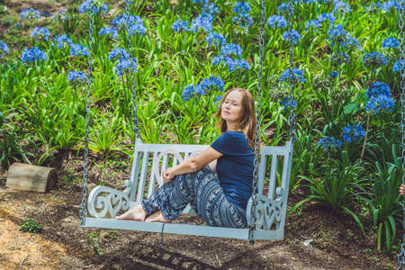 Young woman on a swing in a flower garden.の写真素材