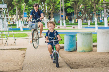 Happy family is riding bikes outdoors and smiling. Father on a bike and son on a balancebike.の写真素材