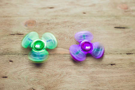 Colored fidget spinners stress relieving toy on wooden background.の写真素材