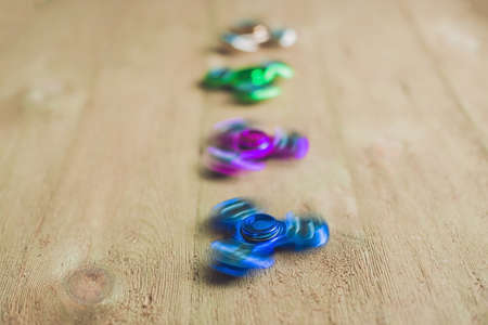 Colored fidget spinners stress relieving toy on wooden background.の写真素材