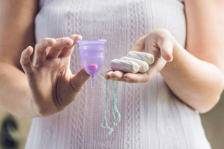 Young woman hands holding different types of feminine hygiene products - menstrual cup and tampons.の写真素材