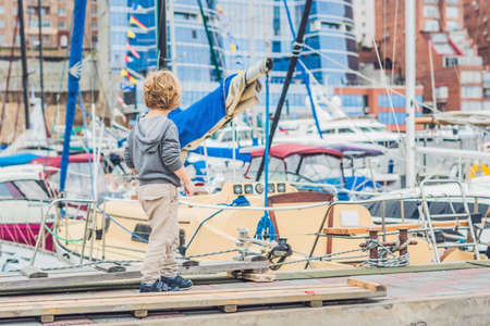 Cute blond boy looking at yachts and sailboats.の写真素材