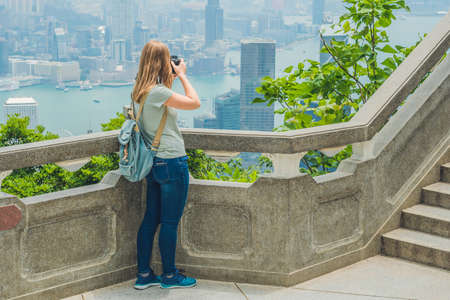 Young woman taking photos of victoria harbor in Hong Kong, China.の写真素材