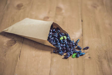 Fresh honeysuckle blue berry fruits with leaf on a wooden background.の写真素材