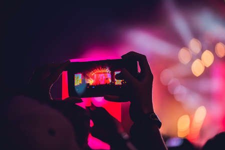 People enjoying rock concert and taking photos with cell phone at music festival.の写真素材