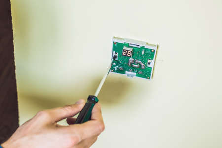 electrician installing an electrical thermostat in a new house.の写真素材