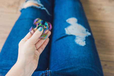 Girl teenager in holey jeans holds in hands and plays with spinner.の写真素材