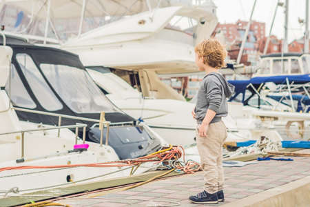 Cute blond boy looking at yachts and sailboats.の写真素材