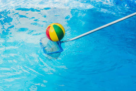 The Toddler boy cleans the pool and pulls the ball out of the pool. Pool Cleaner Concept.の写真素材