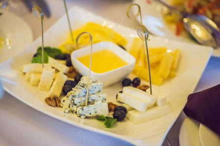 Honey and cheeses on a white plate, food.の写真素材