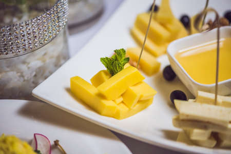 Honey and cheeses on a white plate, food.の写真素材