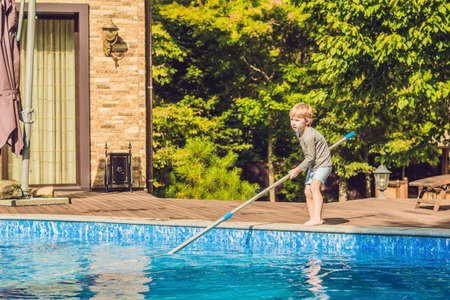 The Toddler boy cleans the pool and pulls the ball out of the pool. Pool Cleaner Concept.