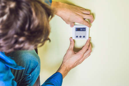 electrician installing an electrical thermostat in a new house.の写真素材