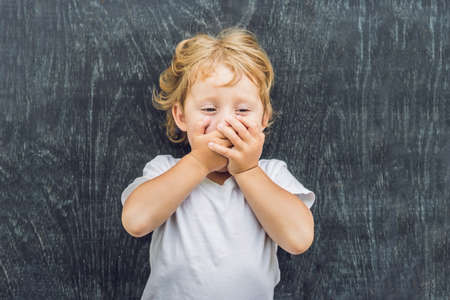 Top view of a little blond kid boy with space for text and symbols on the old wooden background. Concept for confusion, brainstorming and choice. copy spaceの写真素材