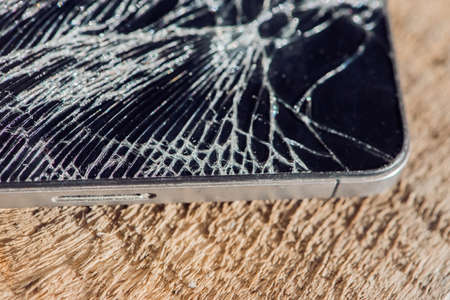 Smartphone display with broken glass on a wodden table.