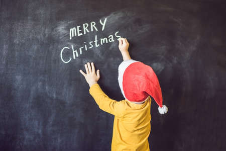 The boy wrote an inscription Merry Cristmas. Christmas tree. Xmas child and New Year holiday Merry Cristmas your familyの写真素材