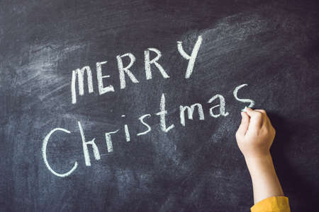 The boy wrote an inscription Merry Cristmas. Christmas tree. Xmas child and New Year holiday Merry...