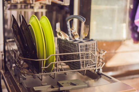 Dishwasher with dirty dishes. Powder, dishwashing tablet and rinse aid. Washing dishes in the...