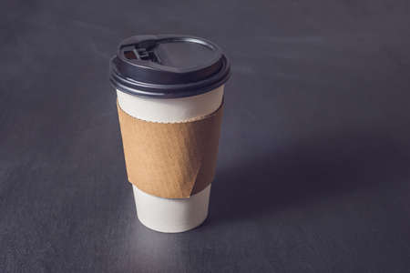 White paper cup for coffee on a black background.