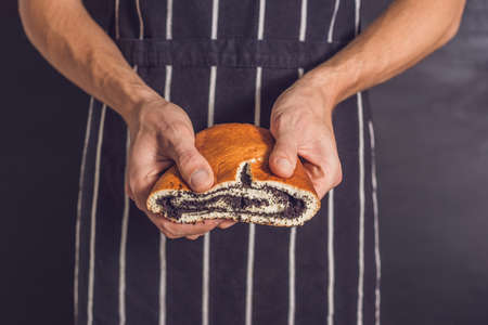 Roll with poppy seeds in the hands of a baker.の写真素材