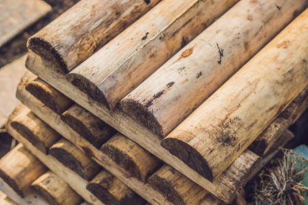 Folded in wooden piled beige beech boards, uneven bars background in a sawmill. Sawn-off boards.