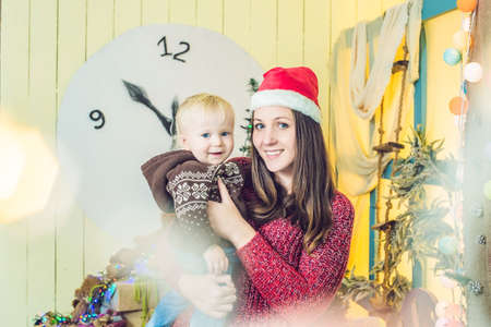 Portrait of happy mother and adorable baby celebrate Christmas. New Year's holidays. Toddler with mom in the festively decorated room with Christmas tree and decorations.の写真素材