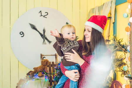 Portrait of happy mother and adorable baby celebrate Christmas. New Year's holidays. Toddler with mom in the festively decorated room with Christmas tree and decorations.の写真素材
