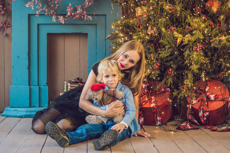 Portrait of happy mother and adorable boy celebrate Christmas. New Year's holidays. Toddler with mom in the festively decorated room with Christmas tree and decorations.の写真素材