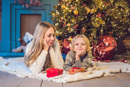 Portrait of happy mother and adorable boy celebrate Christmas. New Year's holidays. Toddler with mom in the festively decorated room with Christmas tree and decorations.の写真素材