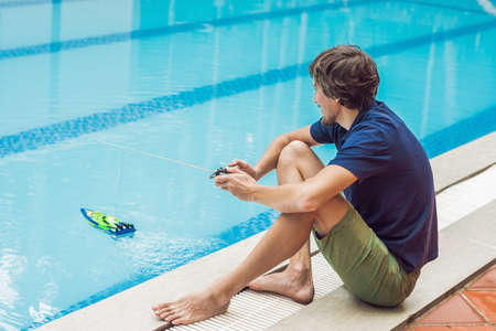 Man playing with a remote controlled boat in the pool.の写真素材