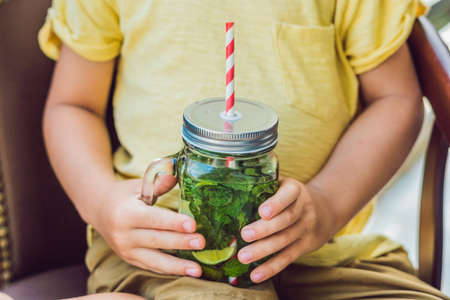 A little boy drinks water with mint and lime. Drink more water concept.の写真素材